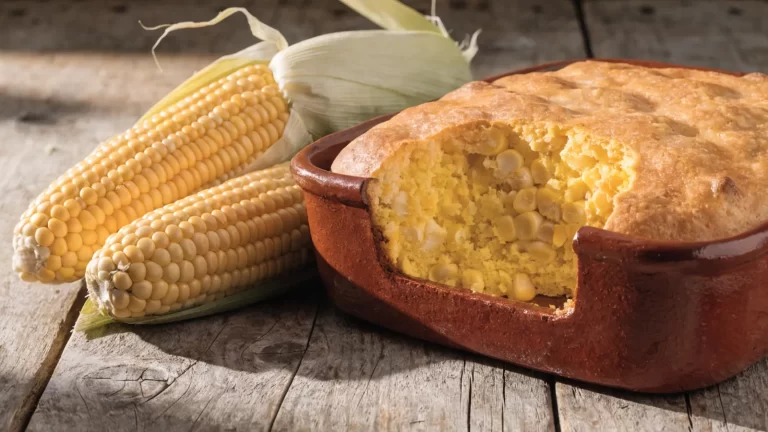 Chipa guasu recién horneada en fuente de barro, con choclos al costado