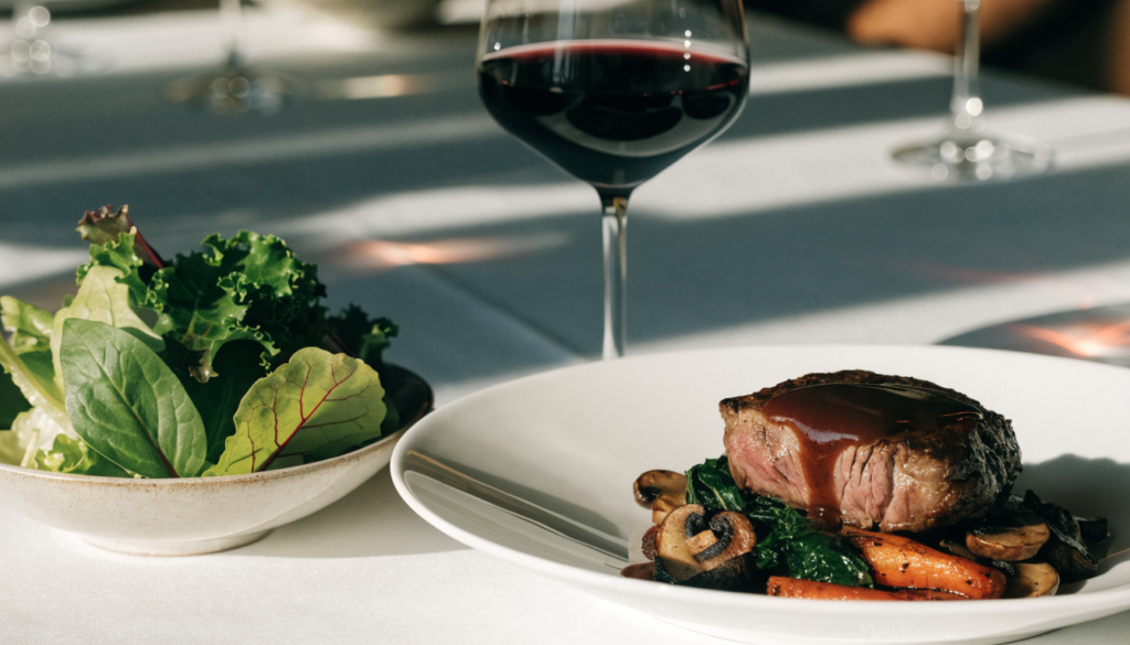Mesa de restaurante servida con plato principal, guarnición y bebida. Imagen ilustrativa: no corresponde al local.