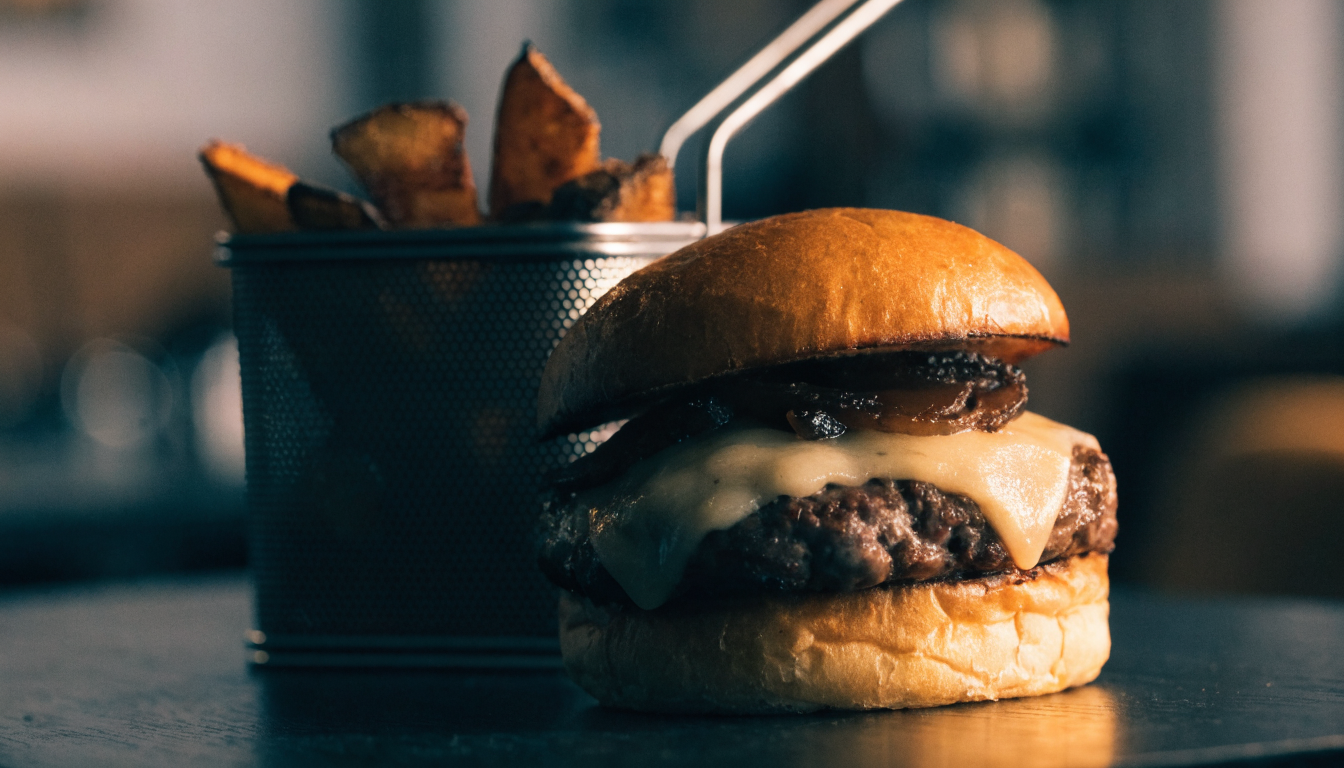 Hamburguesa artesanal con queso derretido y papas fritas rústicas en canasta. Imagen ilustrativa: no corresponde al local.