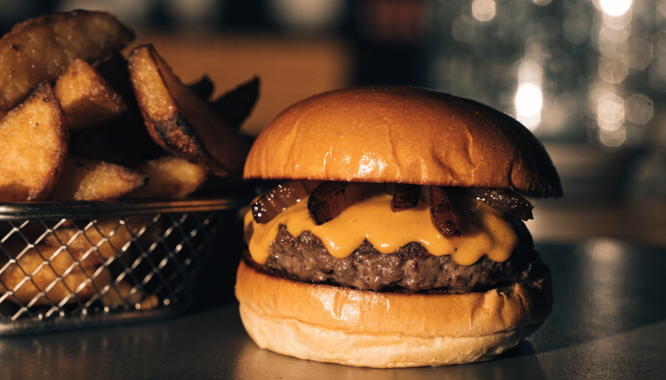 Hamburguesa artesanal con queso derretido y papas fritas rústicas en canasta. Imagen ilustrativa: no corresponde al local.